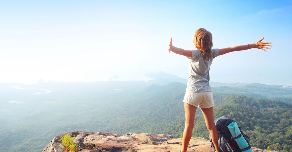 Digitale Nomadin und Backpackerin mit Lebensfreude auf einem Berg